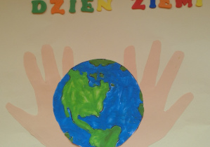 Kolorowanka przedstawiająca kulę ziemską na tle wyciętych z papieru dłoni. Na górze napis: Dzień Ziemi